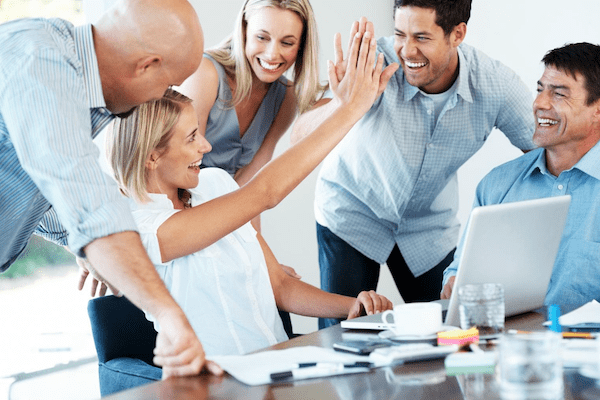 group of excited coworkers giving high fives to each other