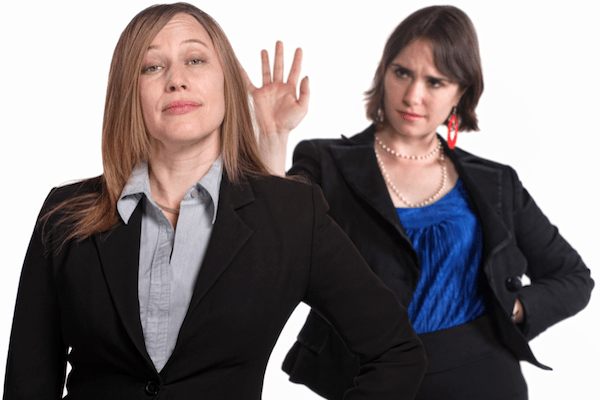 two women in business suits. One is smug and the other is disgusted with her
