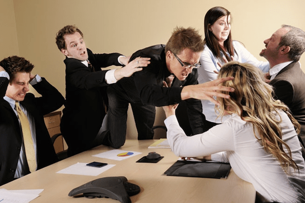 group of professionals in suits in a fight with a man lunging across the table and attacking a woman while others try to hold him back