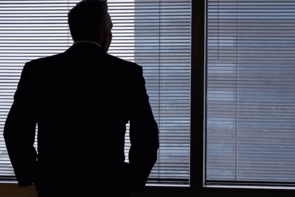 business man silhouetted in window of skyscraper