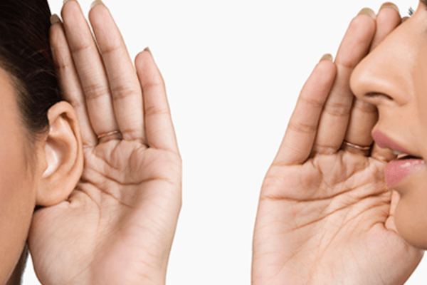 woman with hand up saying something into another person' cupping their ear as if listening