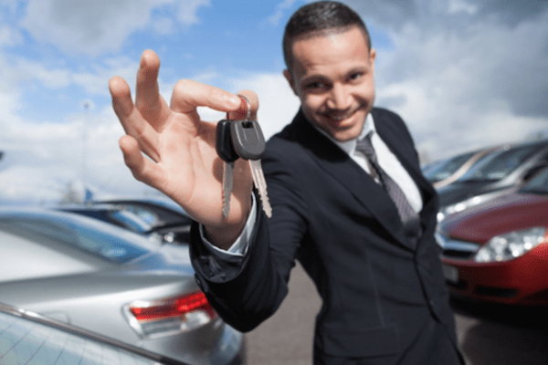 man holding keys surrounded by cars