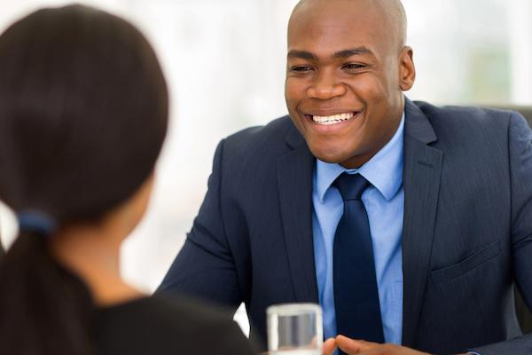black man in suit smiles at woman across from him