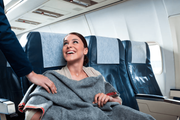 airplane passenger smiling at an airline server who brought her a blanket