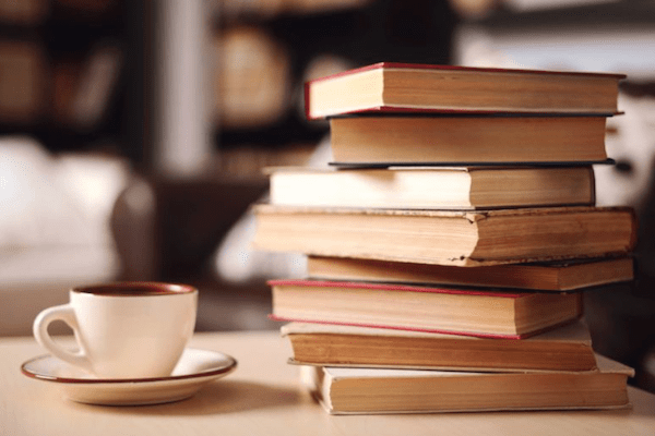 stack of books next to cup of coffee