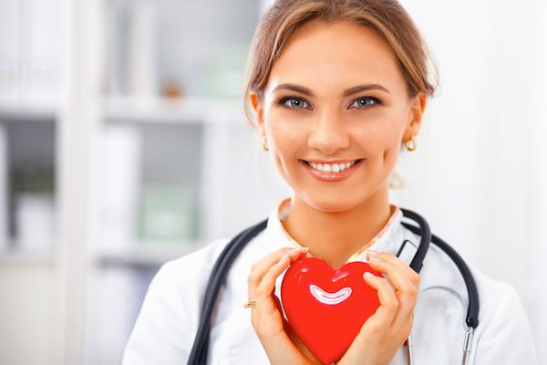 medical woman with stethoscope holding a shiny red heart
