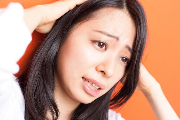 Asian woman looking upset holding her head