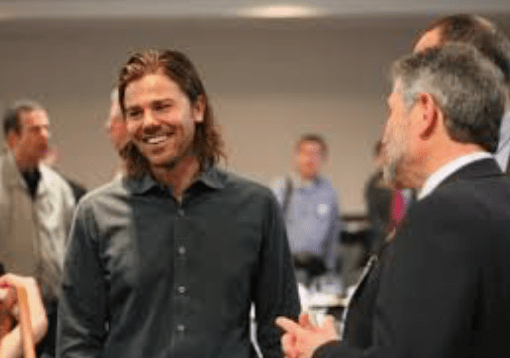 man smiling in a group of people listening to him