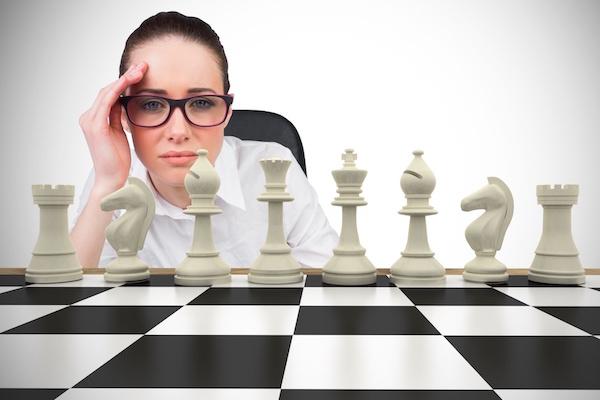 professional woman staringat a chess board as if straining to figure out next move