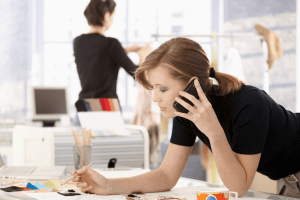 woman on phone at work writing something down