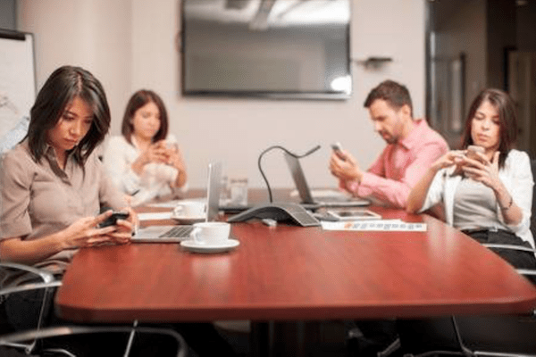 four people all focusing on their phone separately