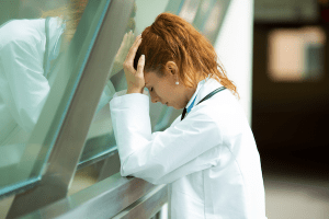 Health worker holding head and looking discouraged