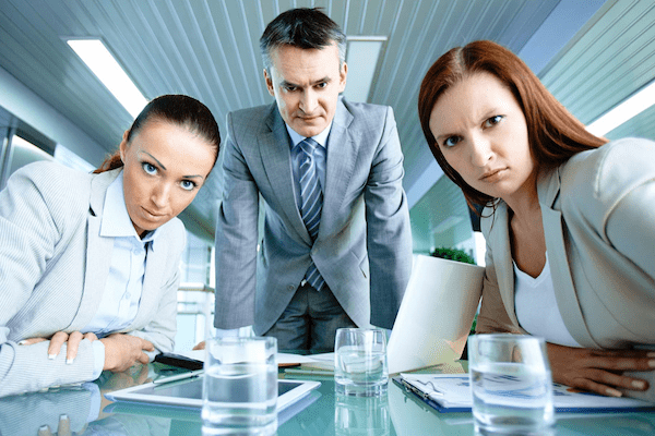 Three people in professional suite glaring at a screen