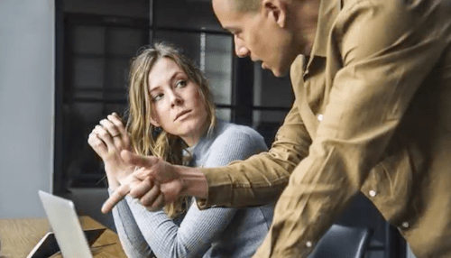 man reprimanding woman coworkers pointing his finger at a laptop