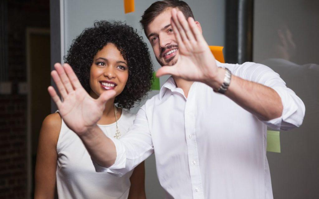 smiling man framing hands to share a vision with a woman