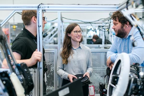 young woman smiling and talking with two younger men