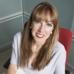 woman in chair in corner looking up and smiling