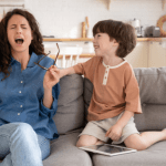 Mom and son on the couch, Mom is screaming and son is smiling