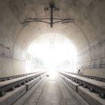 brown tunnel with rail tracks and light at the end of the tunnel