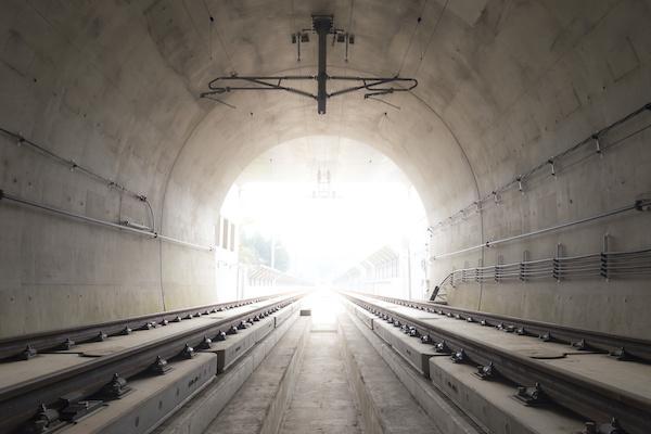 brown tunnel with rail tracks and light at the end of the tunnel